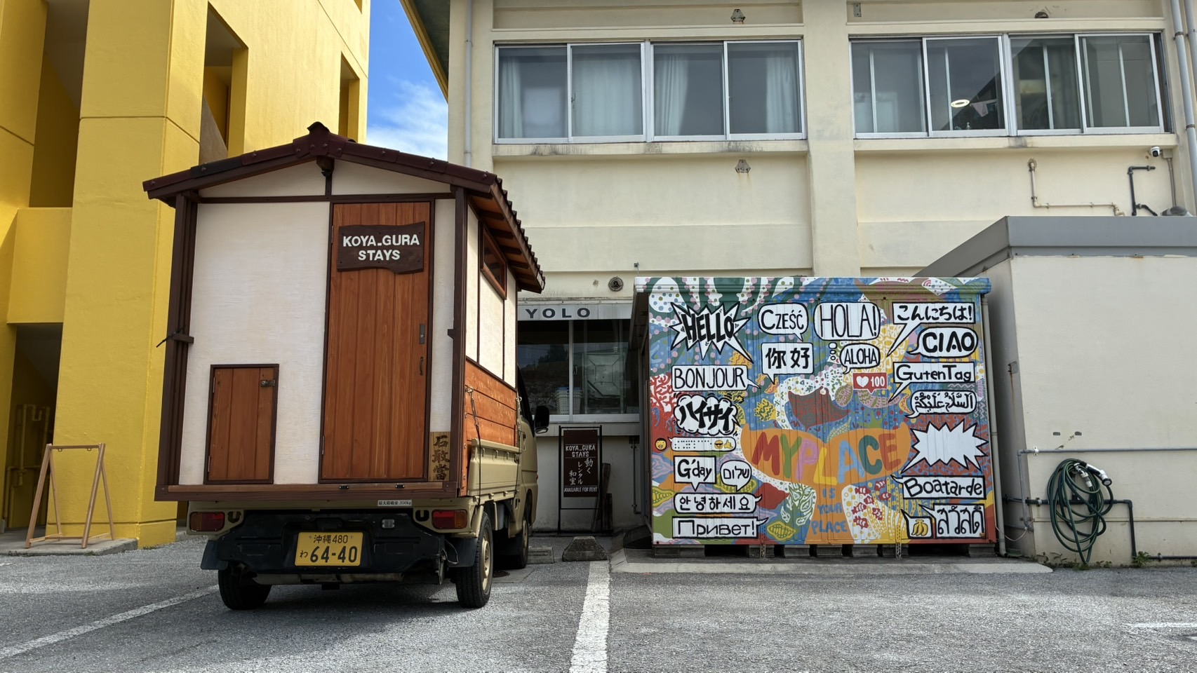 貸渡拠点マイプレイスの前に停まる小屋「かふう」と、世界のあいさつが描かれた壁画
